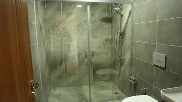 Un box de ducha con paredes de vidrio, un inodoro y un lavabo.