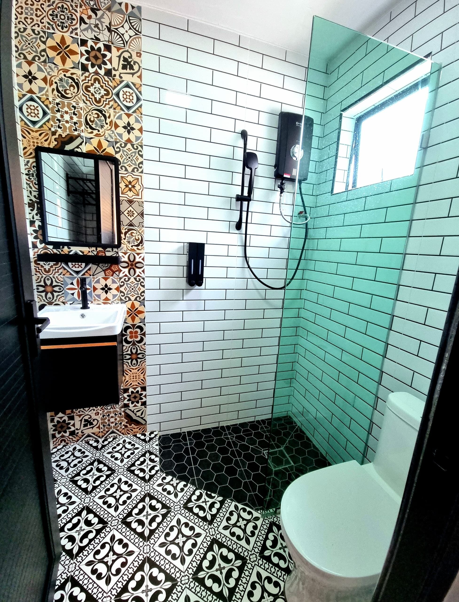 Un bagno con pavimento piastrellato, un lavandino, uno specchio e una zona doccia.