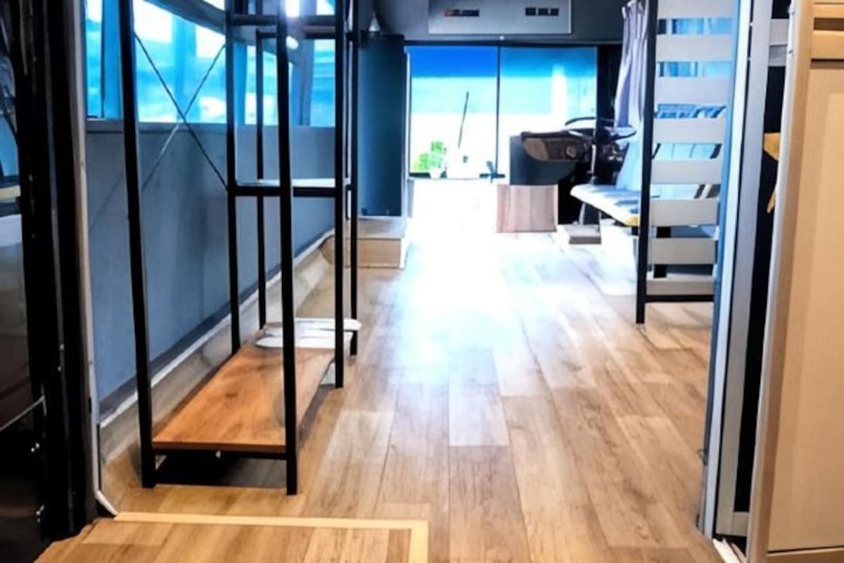 A modern hotel interior with a wooden floor, metal-framed furniture, and large windows.