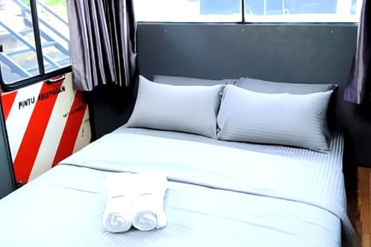 A bed with white bedding and pillows, a window with curtains, and a wall with a red and white striped sign.
