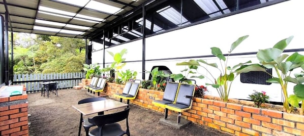 A covered outdoor seating area with brick walls and plants. - Campod Resort (Tanah Rata)