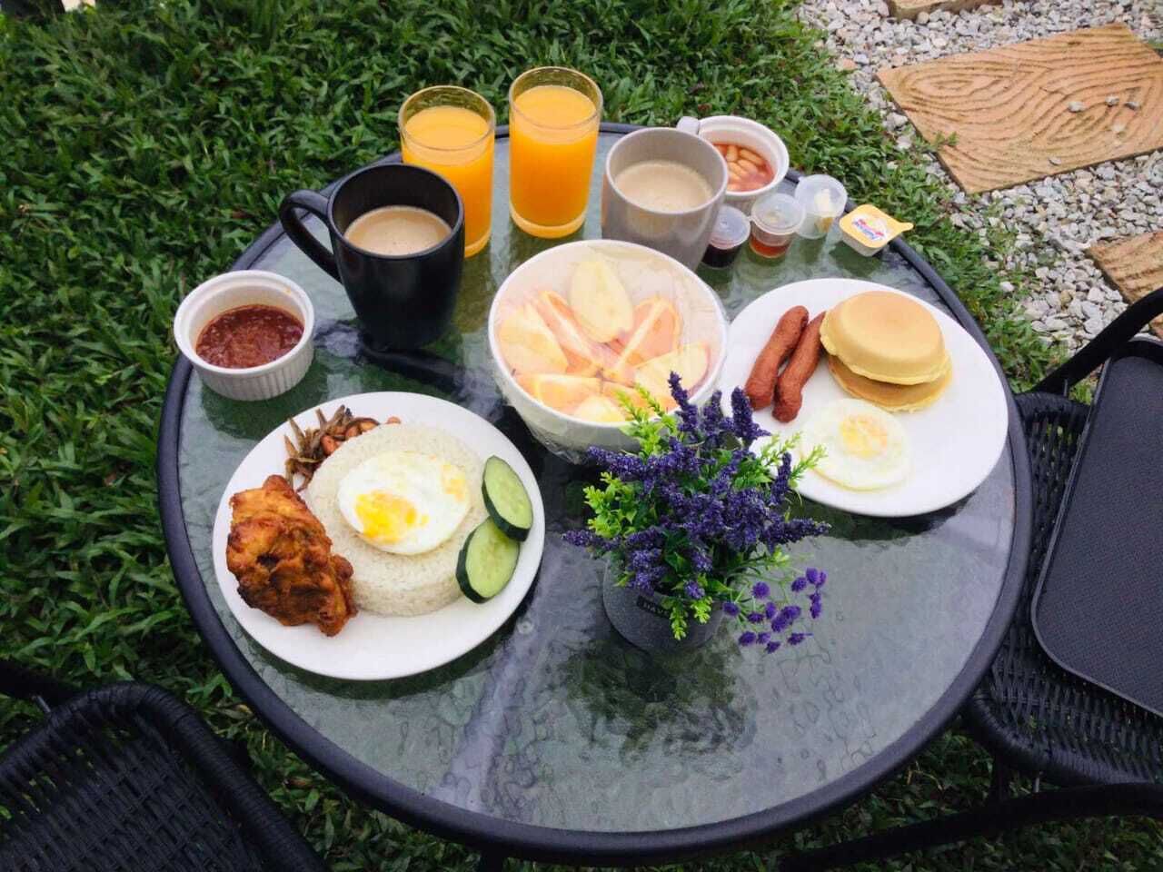 Una mesa con alimentos para el desayuno, como pollo frito, huevos y panqueques, además de bebidas y salsas.