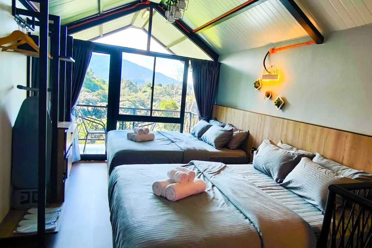 A hotel room with two beds, a balcony, and a view of the outdoors.