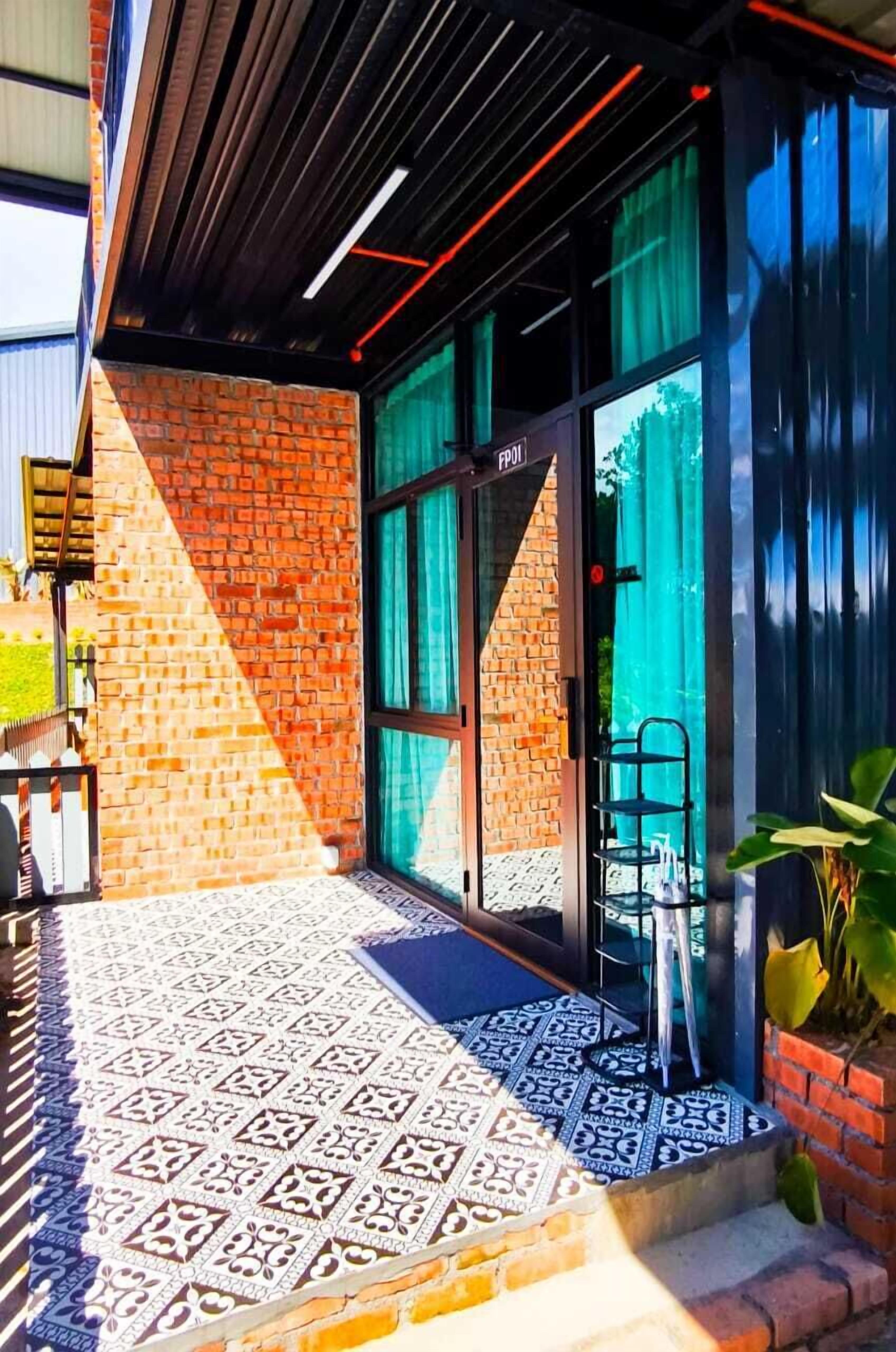 A building entrance with a glass door, a patterned floor, and a brick wall.