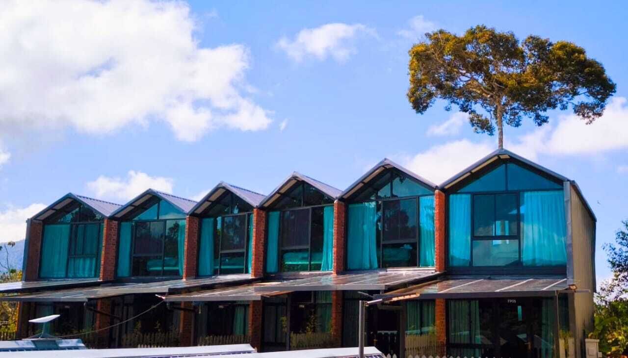 A modern building with multiple glass-walled units and a tree in the background.