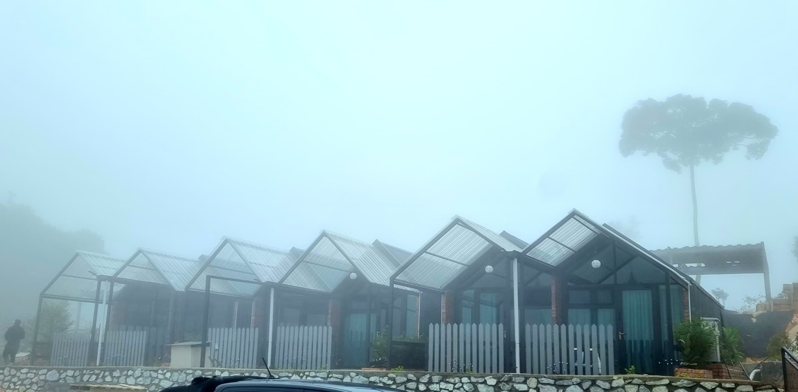 A row of glass-paneled structures with a stone foundation, likely a greenhouse or conservatory.