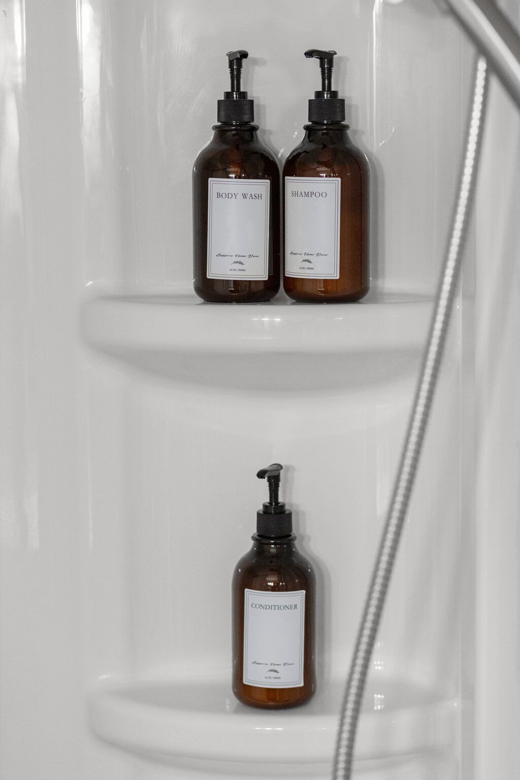 Deux bouteilles de gel douche et de shampoing sont posées sur une étagère blanche dans une salle de bain.
