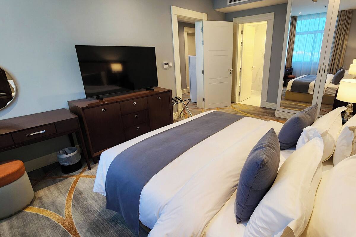 A hotel room with a bed, a TV, a dresser, and a mirror.
