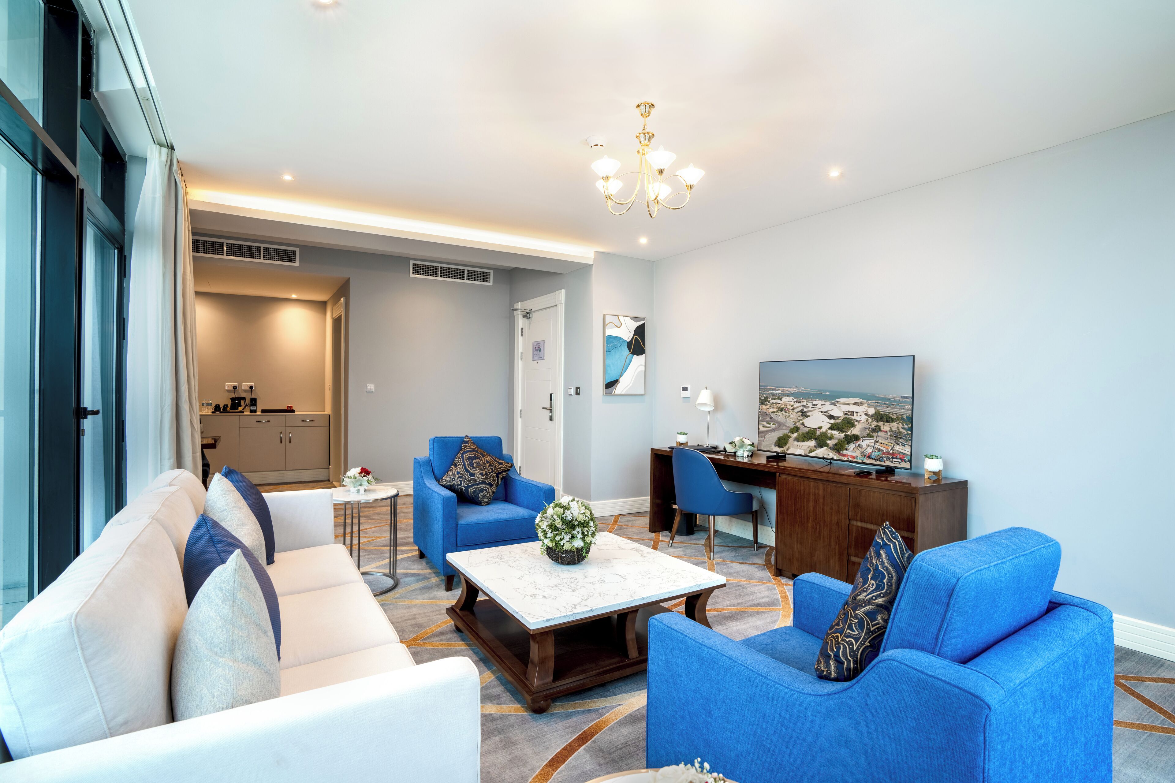 A modern living room with a sofa, armchairs, a coffee table, and a TV.