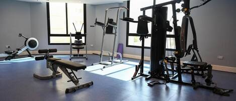A gym with various exercise equipment, large windows, and a clean, modern design.