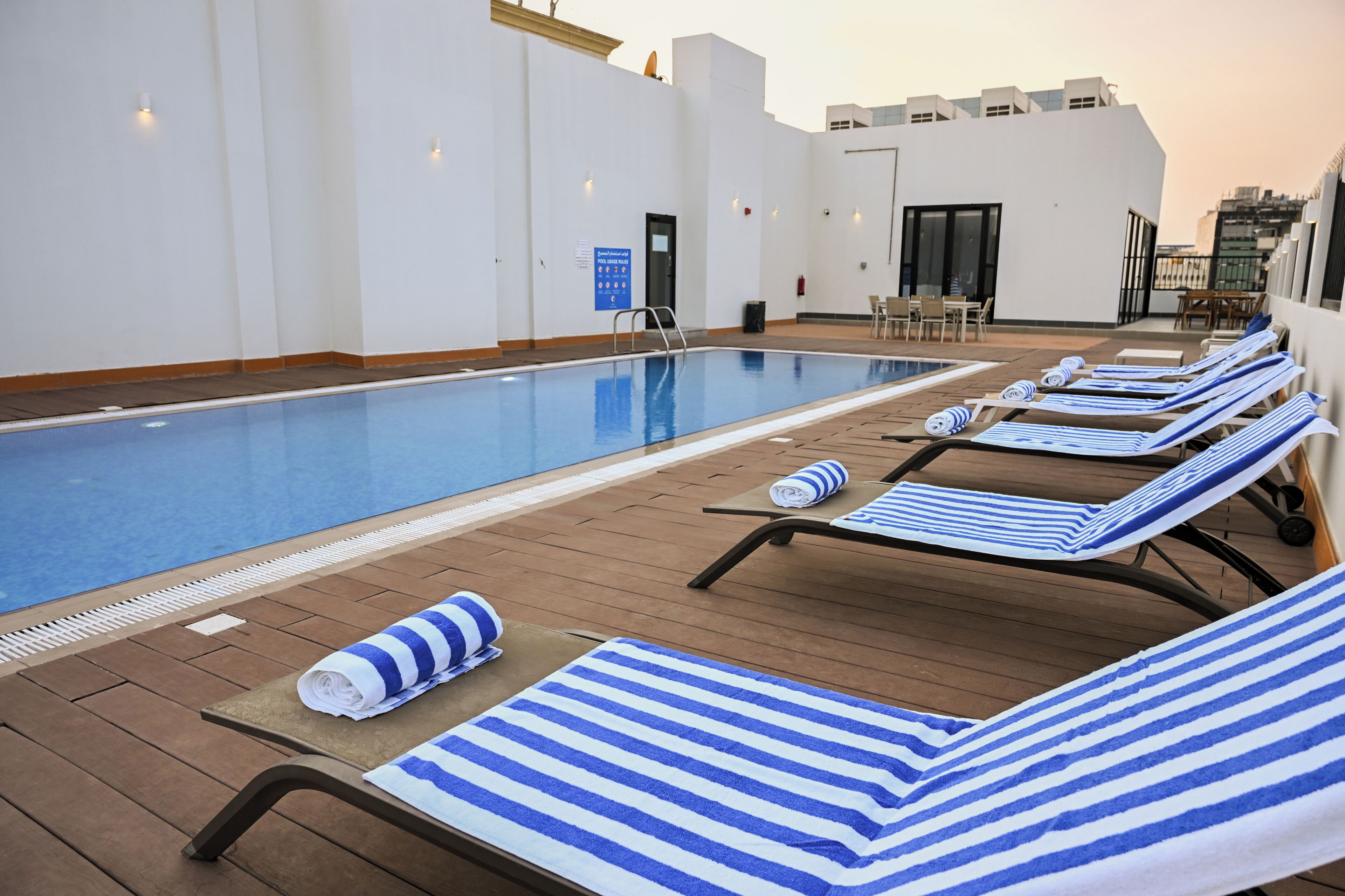 A rooftop pool area with lounge chairs and towels.