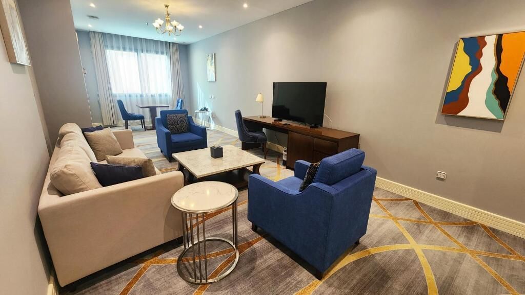 A modern living room with a sofa, armchairs, a coffee table, and a TV.