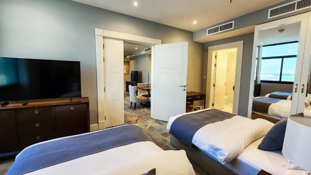 Una habitación de hotel con dos camas, televisión, escritorio y baño.