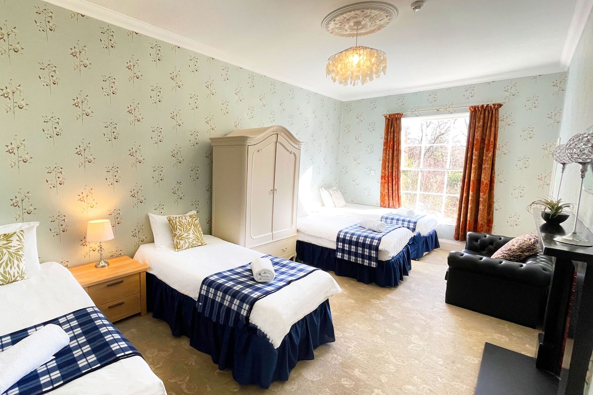 A hotel room with two beds, a wardrobe, a desk, and a chair.