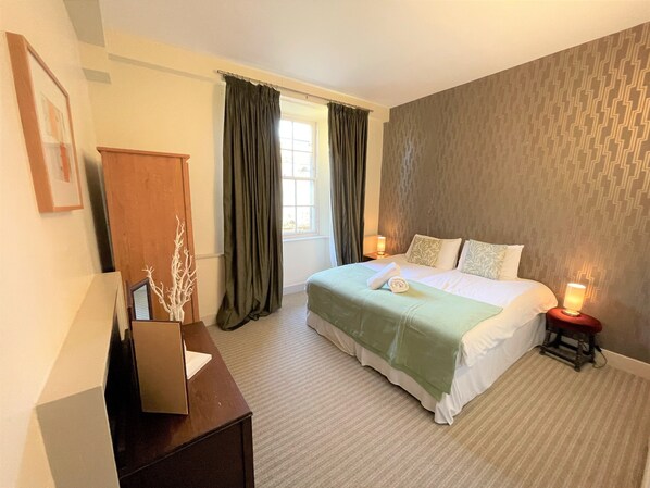A bedroom with a bed, a nightstand, a dresser, and a window with curtains. - Kirkhill Estate Rooms (Gorebridge)