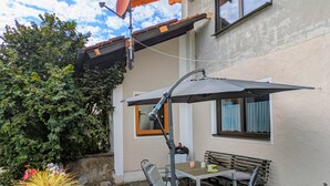 Eine Terrasse im Freien mit Tisch und Stühlen, einer Satellitenschüssel und einem Blumentopf.