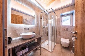 Enjoy a refreshing shower in the sleek shower enclosure with a glass door, complemented by a large sink and ample storage.