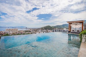 An infinity pool with a view of a cityscape and mountains.