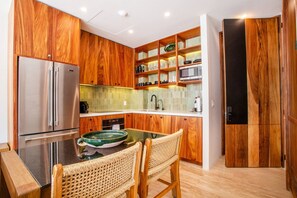 A modern kitchen with wooden cabinetry, stainless steel appliances, and a dining area with wicker chairs. - Ocean View Retreat | Steps to Romantic Zone & Beach (Puerto Vallarta)