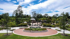 A landscaped area with a circular brick pathway, a central garden, and a building with a sail-like structure. - Sunset Rentals | Forest Beach Villa 415 (Hilton Head Island)