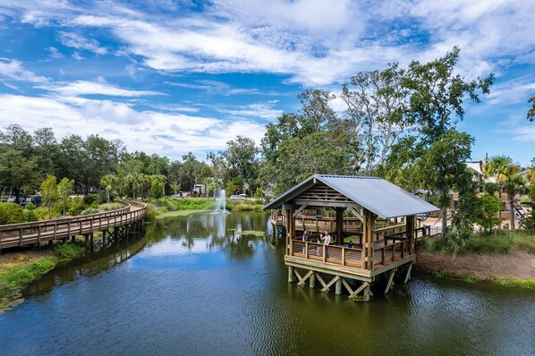 A wooden cabin on stilts over a calm lake, surrounded by lush greenery and trees. - Sunset Rentals | Forest Beach Villa 415 (Hilton Head Island)