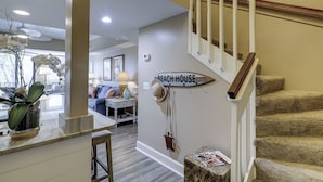 A staircase with a 'Beach House' sign, a dining area with a table and chairs, and a living room with a sofa and decorative items. - Sunset Rentals | Forest Beach Villa 415 (Hilton Head Island)
