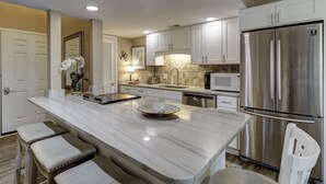 A modern kitchen with a large island, stainless steel appliances, and white cabinetry. - Sunset Rentals | Forest Beach Villa 415 (Hilton Head Island)
