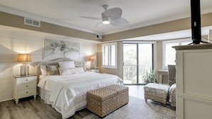 A bedroom with a bed, nightstands, a ceiling fan, a window with blinds, and a balcony. - Sunset Rentals | Forest Beach Villa 415 (Hilton Head Island)