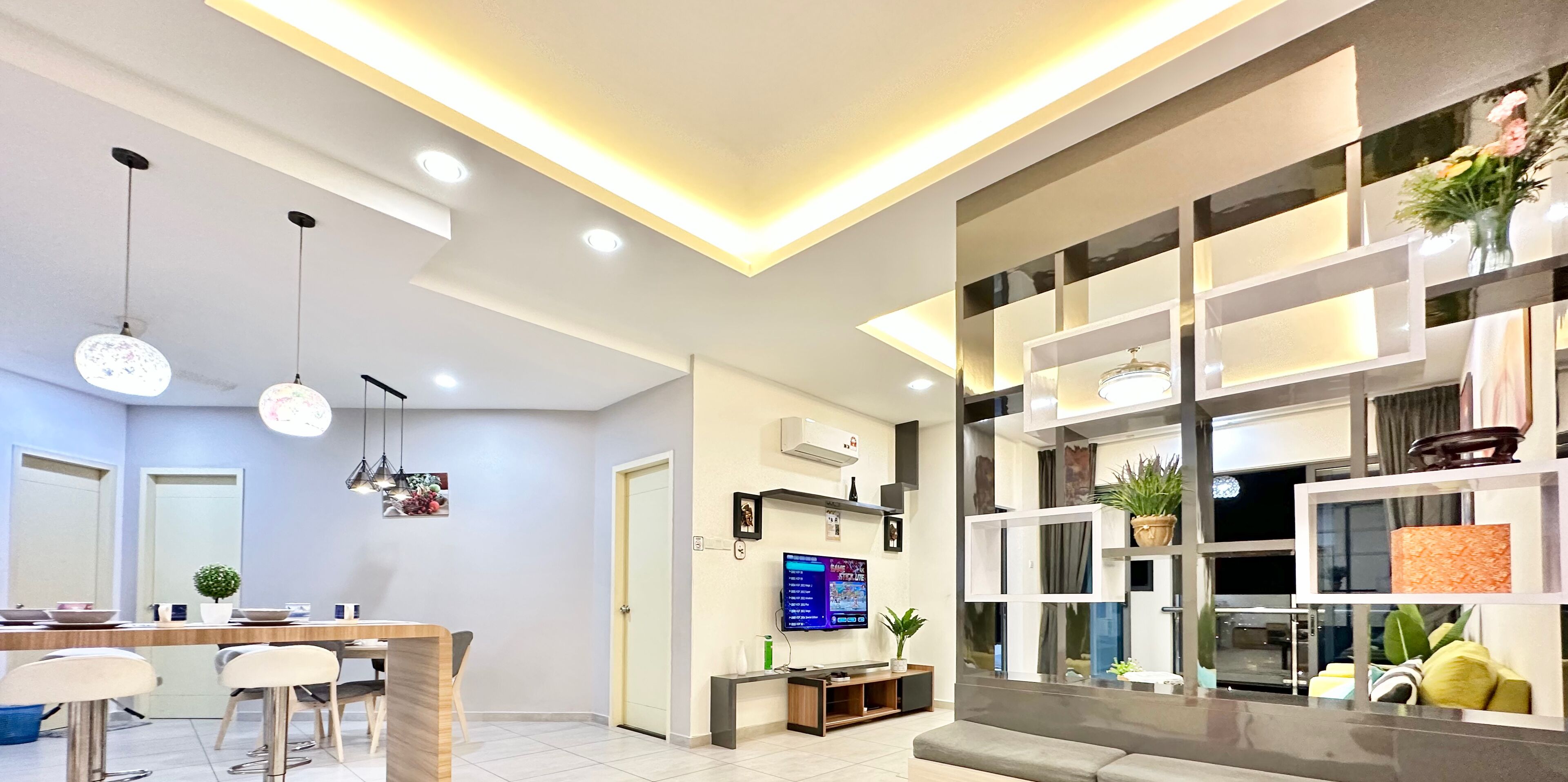 A modern living room with a TV, sofa, and dining area.