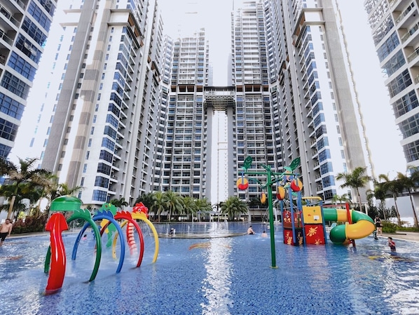 Parque acuático con toboganes y estructuras de juego, rodeado de edificios residenciales altos.