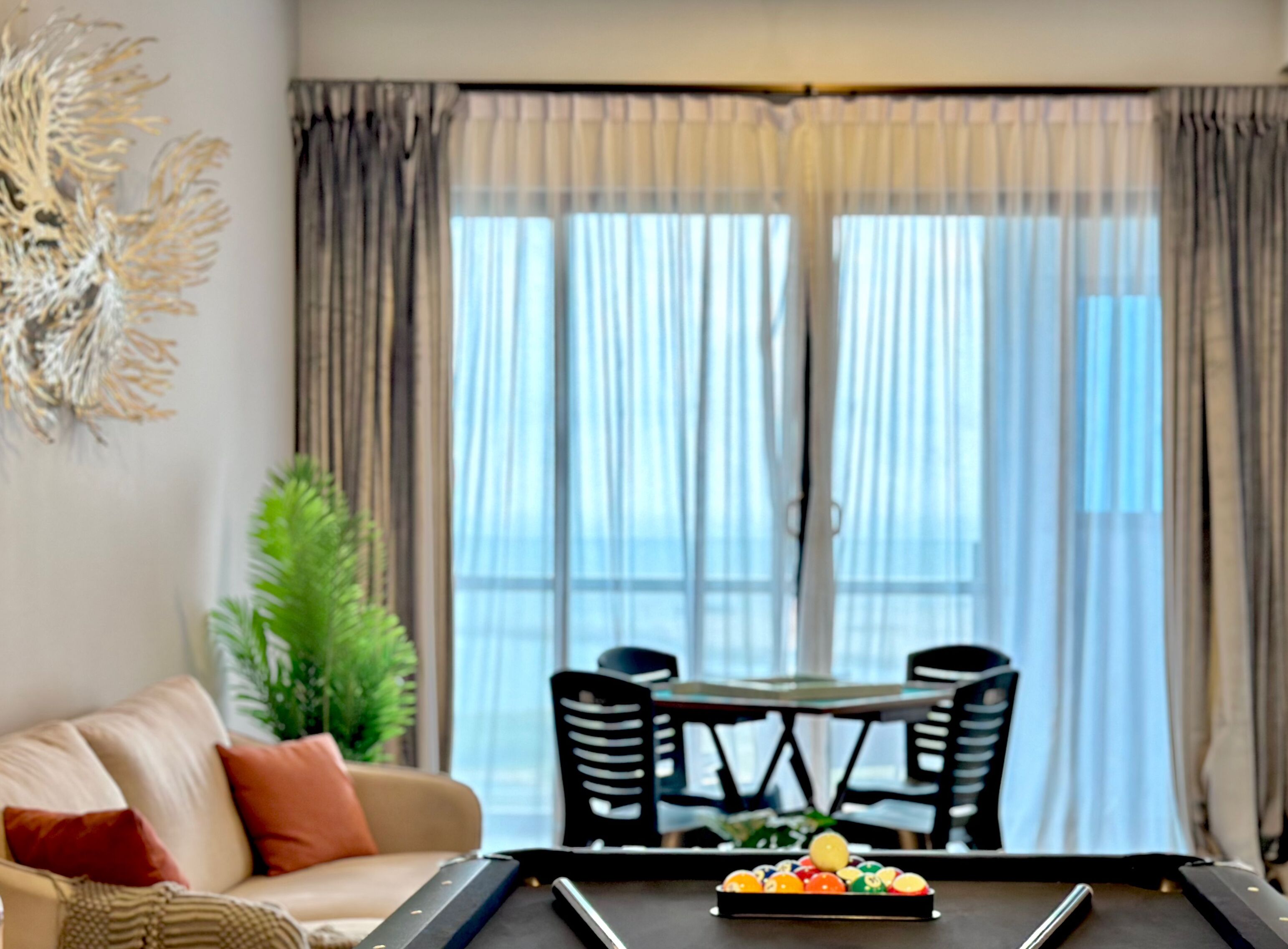 A living room with a pool table, a sofa, and a dining table with chairs.