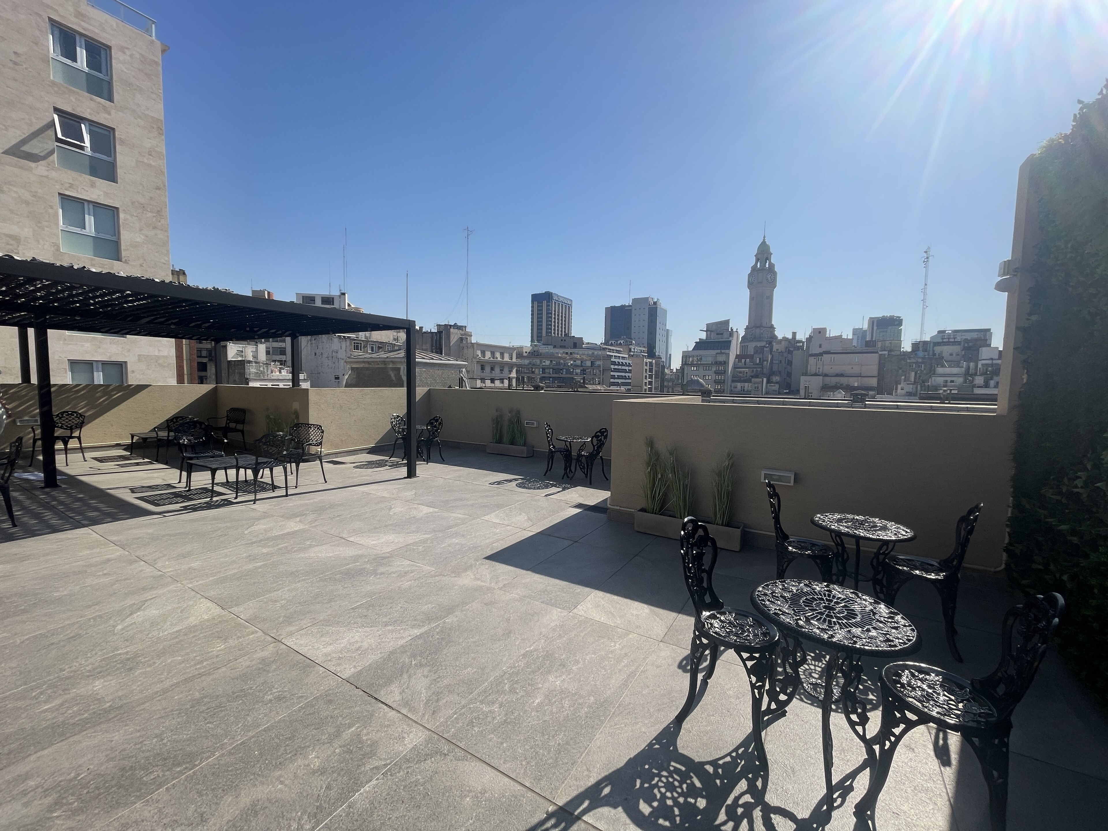 A rooftop terrace with outdoor seating, a pergola, and a city skyline view.