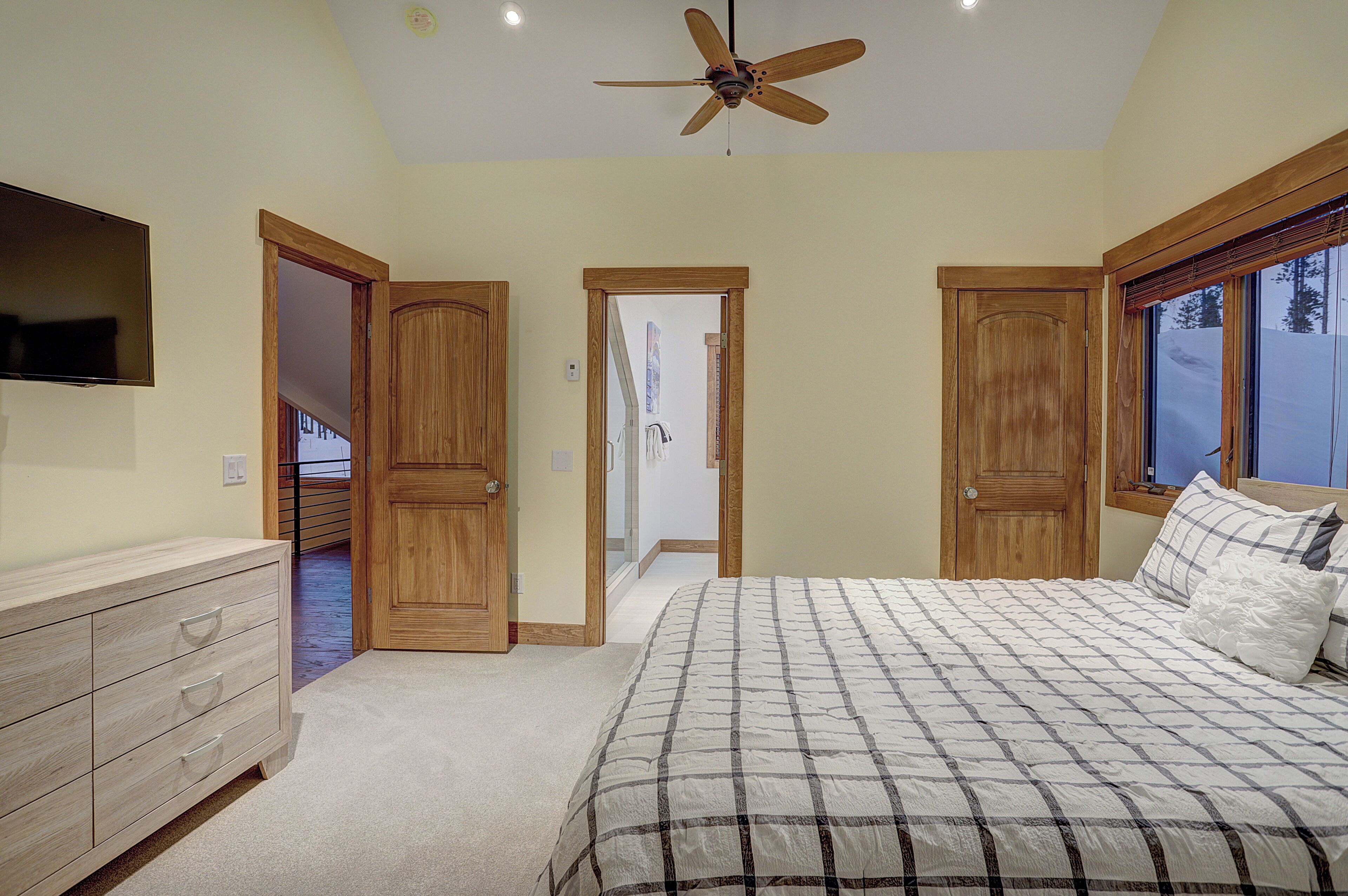 Une chambre à coucher avec un lit, une armoire en bois et un ventilateur de plafond.
