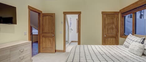 A bedroom with a bed, wooden wardrobe, and a ceiling fan.