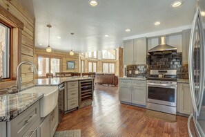 Une cuisine spacieuse agrémentée d’éléments en bois, dotée d’un grand îlot central, d’appareils électroménagers en acier inoxydable et offrant une vue sur l’extérieur.