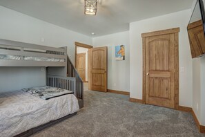 A bedroom with a bunk bed, a wooden door, and a poster on the wall. - Big Blue Trace (Breckenridge)