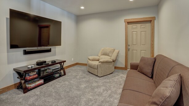 A living room with a flat-screen TV, a recliner, a sofa, and a console table with video games. - Big Blue Trace (Breckenridge)
