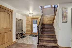 Un escalier en bois menant à une mezzanine où se trouvent un banc et une porte.