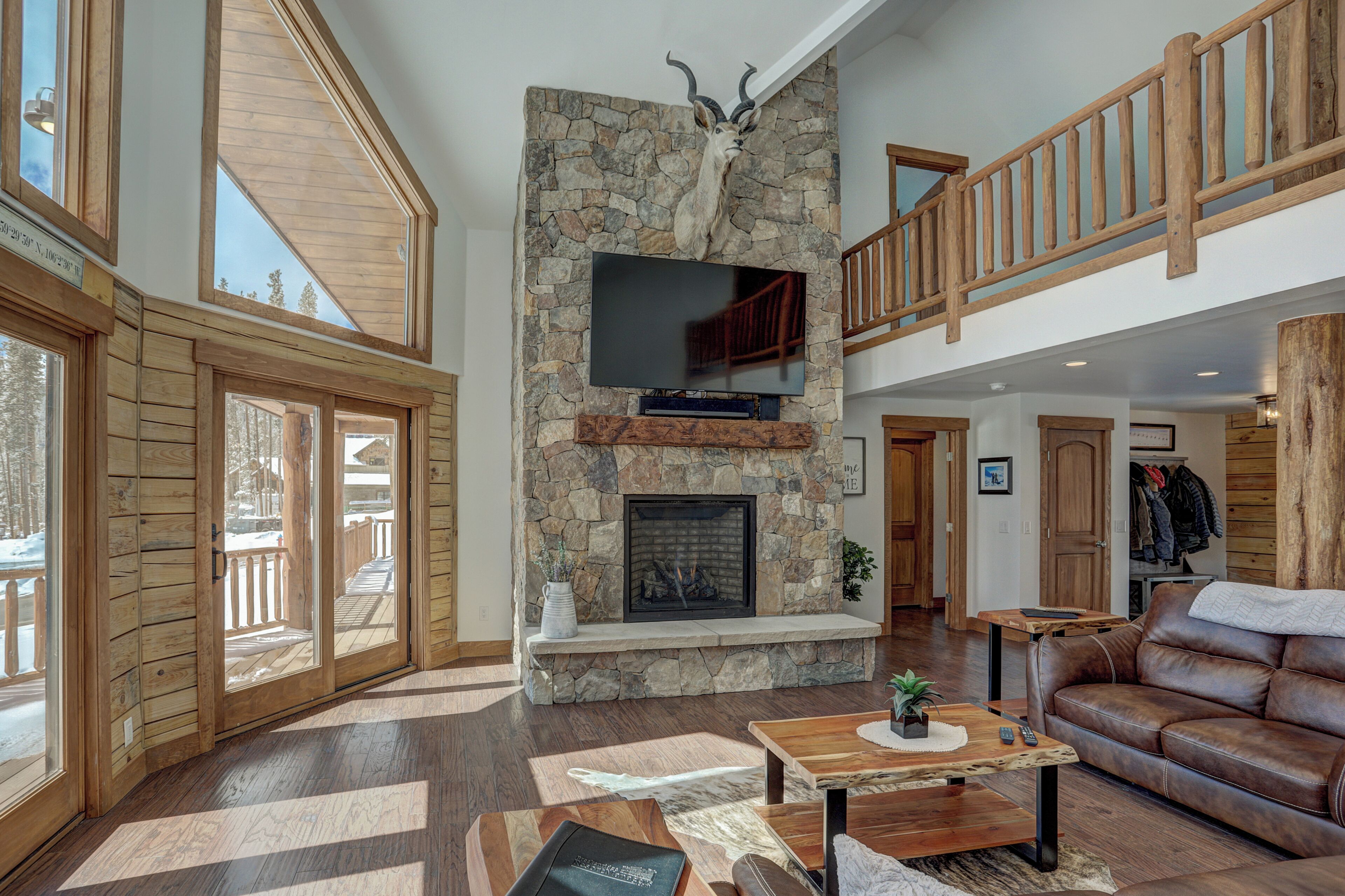A spacious living area with a stone fireplace, wooden flooring, and a leather sofa.