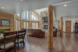 A spacious living area with a stone fireplace, wooden furniture, and large windows offering views of the outdoors. - Big Blue Trace (Breckenridge)
