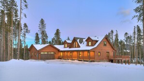 A log cabin with a large deck and multiple windows, surrounded by tall pine trees and snow. - Big Blue Trace (Breckenridge)