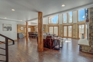 A spacious living area with a wooden floor, a leather sofa, and a stone fireplace.