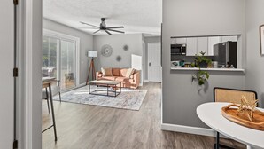 Ein modernes Wohnzimmer mit einer Couch, einem Couchtisch und einem Essbereich mit Tisch und Stühlen.