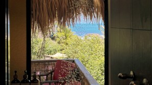 Une salle de bain avec vue sur un jardin luxuriant et l’océan.
