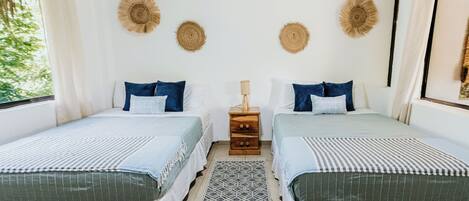 A double room with two beds, a small wooden nightstand, and a patterned rug.
