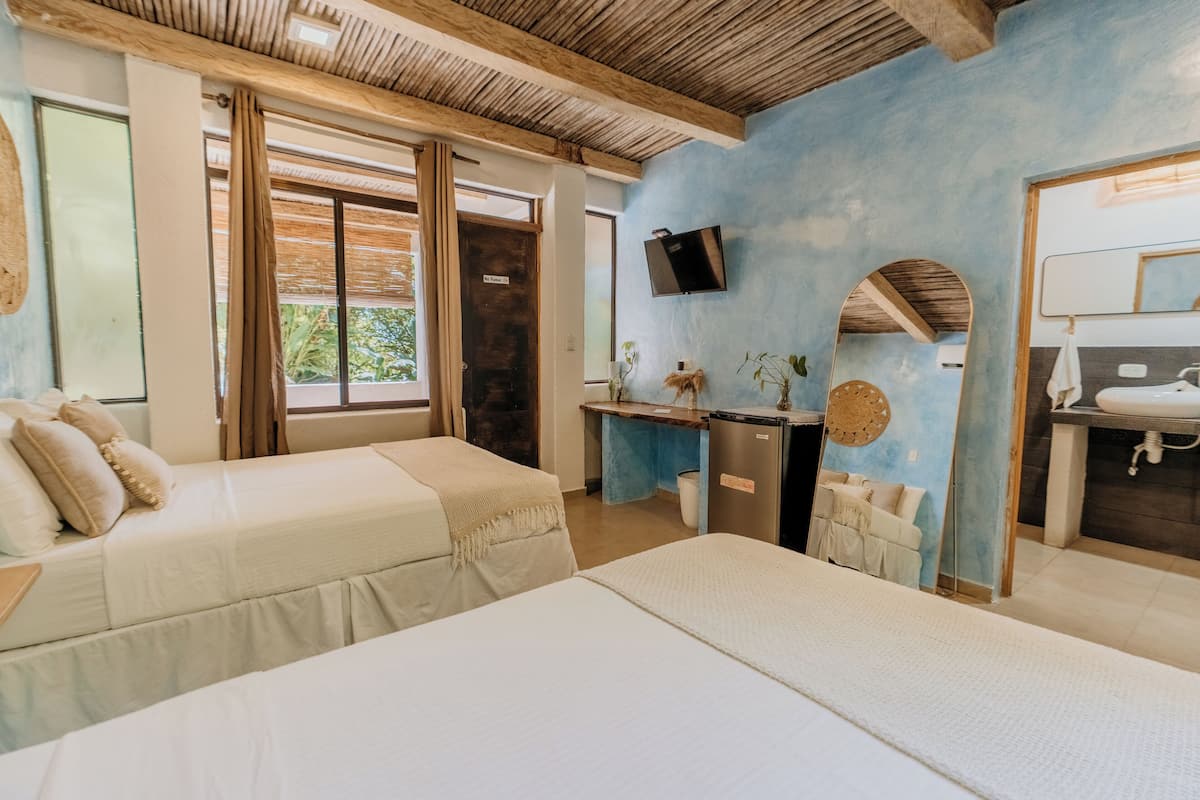 A room with two beds, a desk, a TV, and a bathroom.