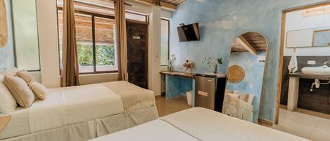 Une chambre avec deux lits, un bureau, une télévision et une salle de bain.