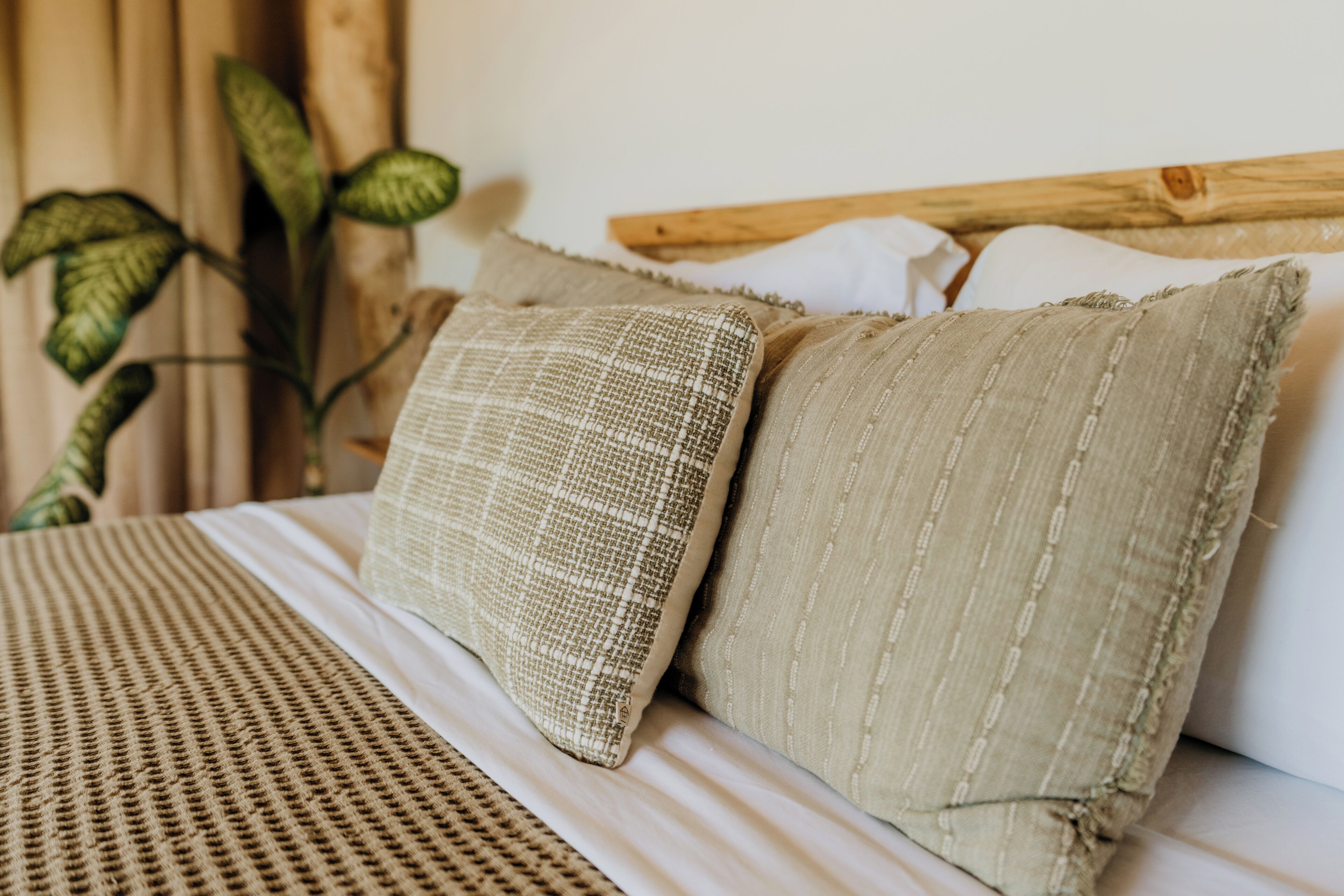 Ein Bett mit einer gewebten Decke und zwei strukturierten Kissen.