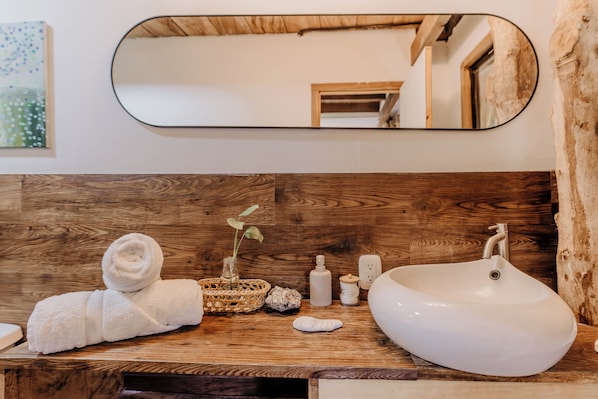 A wooden vanity with a white sink, a mirror, and a towel.