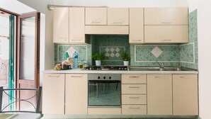 A kitchen with beige cabinets, a gas stove, a sink, and a window with a view of the outside. - 1 Bedroom Apartment in Ischia (Ischia)